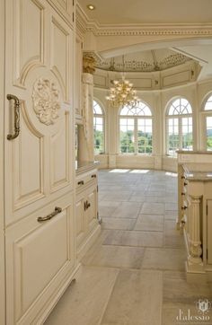 an ornate kitchen with white cabinets and chandelier