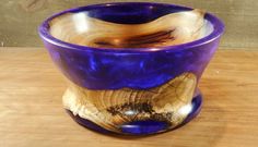 a purple glass bowl sitting on top of a wooden table