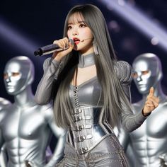 a woman with long gray hair is singing into a microphone while several mannequins are in the background