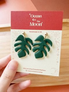 a pair of green leaf earrings sitting on top of a card