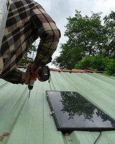 a man working on the roof of a house with a power drill and an electronic device