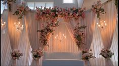 a white couch sitting under a window next to a wall covered in curtains and flowers