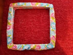 a square frame sitting on top of a red rug