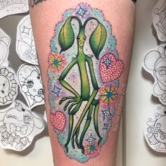 an alien tattoo on the leg of a woman's leg with hearts and flowers