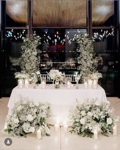 the table is set up with candles and flowers for an elegant wedding reception in front of a large window