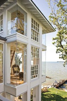 a house on the edge of a body of water with large windows that look out into the ocean