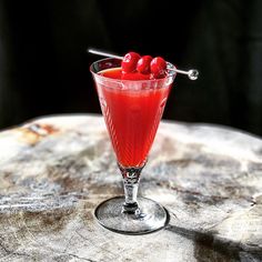 a glass filled with red liquid and cherries