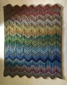 a crocheted afghan with multicolored waves on the front and back side