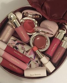 the contents of a purse are neatly arranged in a round container, including lip glosses and lipstick