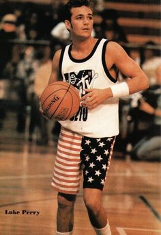 a young man holding a basketball on top of a court with an american flag shorts