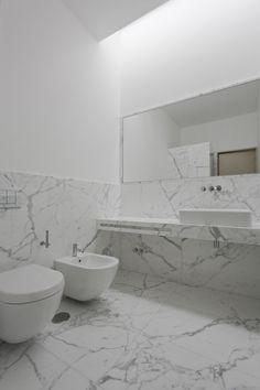 a bathroom with two white sinks and marble counter tops on each side of the wall