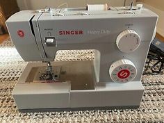 the singer heavy duty sewing machine is sitting on top of a rug next to a wall