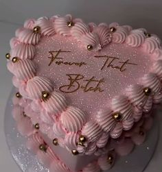 a heart shaped cake with pink frosting and gold decorations