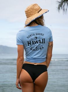 the back of a woman wearing a blue shirt that says north shore and has hawaii written on it