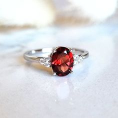 ✨ Extended Holiday Returns & Exchanges ✨ Items purchased between 15st November and 31st December 2024 can be returned or exchanged until 15th January 2025. Absolutely captivating, this stunning ring is made with natural garnet - a deep red gemstone and sparkly simulated diamonds. It is handcrafted in solid sterling silver and plated with rhodium for a lustrous finish and durability. - Natural garnet oval cut 8x6mm (approx. 1.25 carats) - Premium simulated diamonds - Rhodium plated on solid 925 s Garnet Ring Silver, Sterling Silver Garnet Ring, Garnet Engagement Ring, Fall Rings, Red Gemstones, Garnet Ring, Silver Wedding Rings, Cubic Zirconia Rings, Garnet Rings