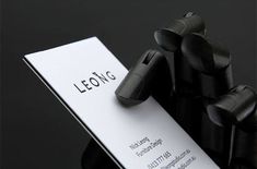 a close up of a business card on a black surface with the name leong printed on it