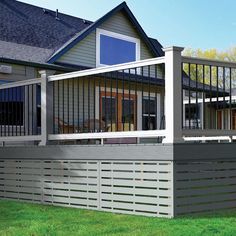 a house with a deck and fence in front of the house on a sunny day