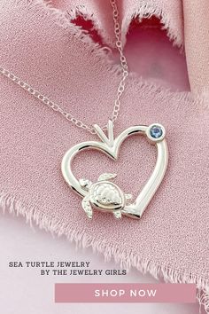 a heart shaped pendant on a pink cloth with a blue crystal stone in the center