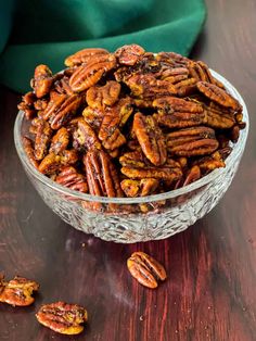 a glass bowl filled with pecans on top of a wooden table