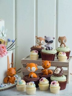 cupcakes with frosting and animal figurines are on display