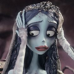 a creepy doll with her hands on her head and eyes painted black, white and grey