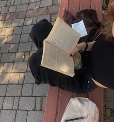 a woman sitting on a bench reading a book