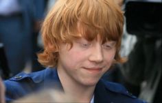 a close up of a person with red hair wearing a blue shirt and looking at the camera