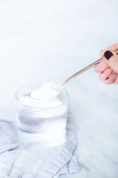 a person is holding a spoon over a glass of water