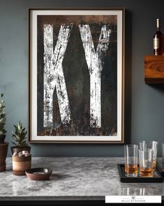 a kitchen counter with glasses on it and a framed letter k in the middle above