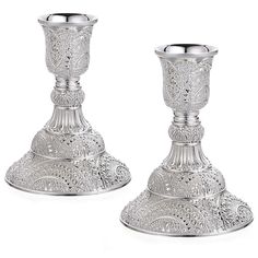 two silver candlesticks sitting next to each other on top of a white surface