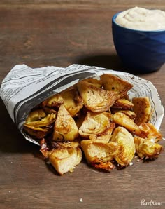 some food is sitting on a table next to a blue bowl and napkin with dip in it