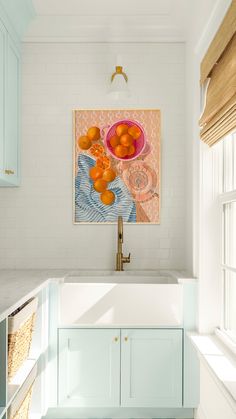 a kitchen with blue cabinets and white countertops has oranges in a bowl on the sink