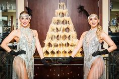 two women dressed in flap dance costumes standing next to a christmas tree with lights on it