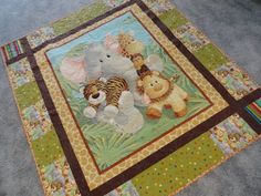 there is a baby quilt with animals and bears on the floor in front of it