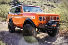 an orange jeep driving down a dirt road