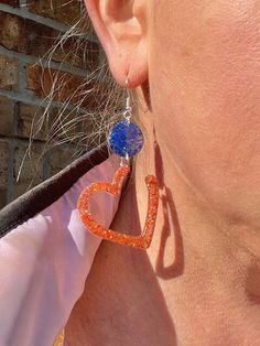 Show your Astros pride with these adorable handmade heart earrings! Crafted with resin and glitter, these earrings sparkle with the team's classic blue and orange colors. Choose from pierced or clip-on styles for a comfortable fit that works best for you. These heart earrings are perfect for game days, team events, or just whenever you want to add a pop of Astros spirit to your look. They also make a thoughtful gift for any Astros fan in your life. Let your love for the team shine bright with th Word Earrings, Heart Glitter, Resin Earring, Earrings Sparkle, Handmade Heart, Sparkle Earrings, Memory Wire Bracelets, Handmade Jewelry Gift, Wire Bracelet