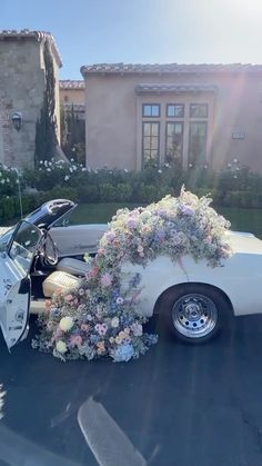 a white car parked in front of a house with flowers on the side of it