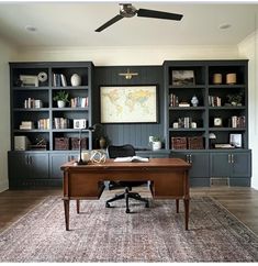 a home office with built - in bookcases and a rug