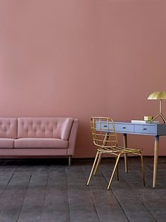 a living room with pink walls and gold furniture in front of a blue table that has a lamp on it