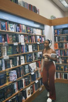 a woman standing in front of a bookshelf with headphones on her ears