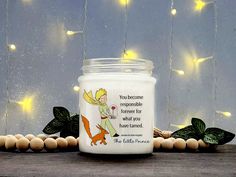 a candle with a fairy on it sitting next to some leaves and lights in the background