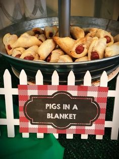 a bowl filled with pigs in a blanket on top of a table next to a sign that says pigs in a blanket