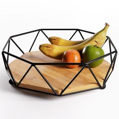 two bananas and three oranges in a wire basket on a cutting board with a wooden tray