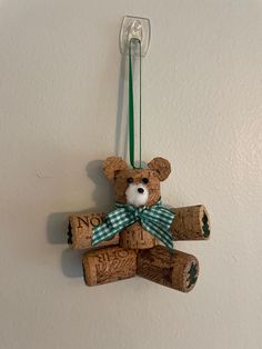 a brown teddy bear with a green bow on it's neck hanging from a wall