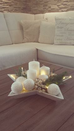 a table with candles and decorations on it in front of a couch, which is also an instagram