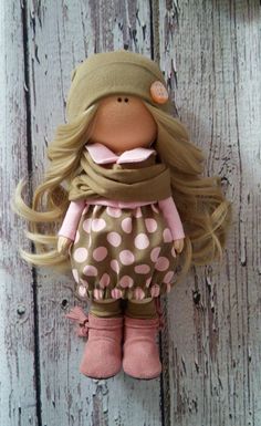 a doll with blonde hair and polka dot pants hanging on a wooden door knobs