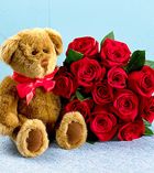 a teddy bear sitting next to a bouquet of roses with the words happy holidays written on it