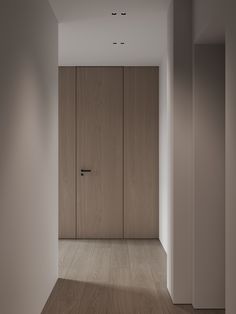 an empty room with wooden doors and white walls, in the middle of it is a light wood floor