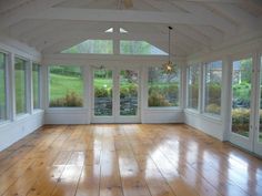 an empty room with wood floors and large windows