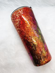 a red and gold glittered cup sitting on top of a white fur covered floor